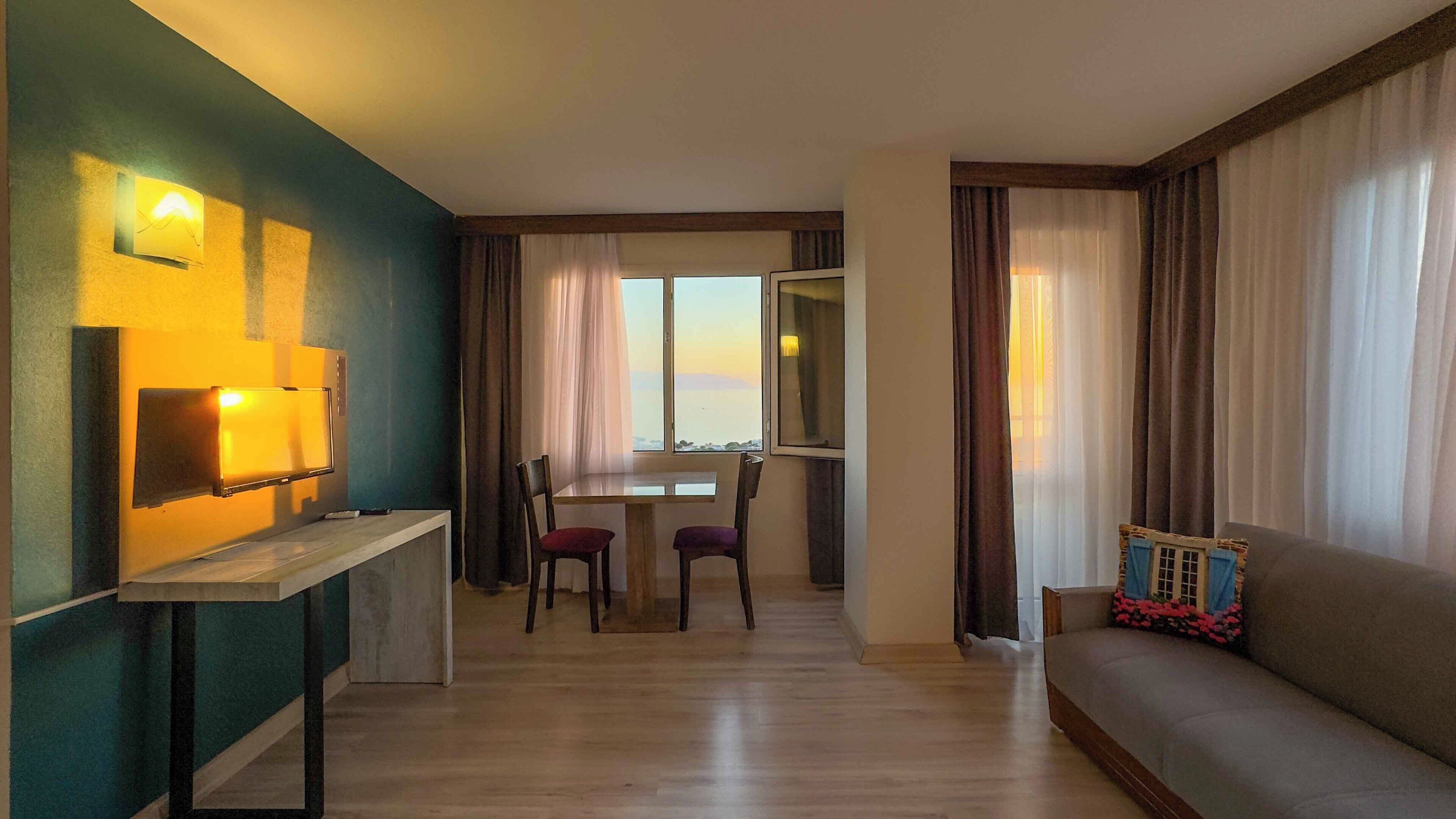 Una sala moderna con un sofá, una mesa de comedor con sillas y un televisor montado en la pared.
