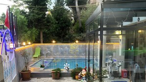 A rooftop pool area with a glass enclosure, potted plants, and outdoor seating. - La Bella Suite Hotel (Kusadasi)