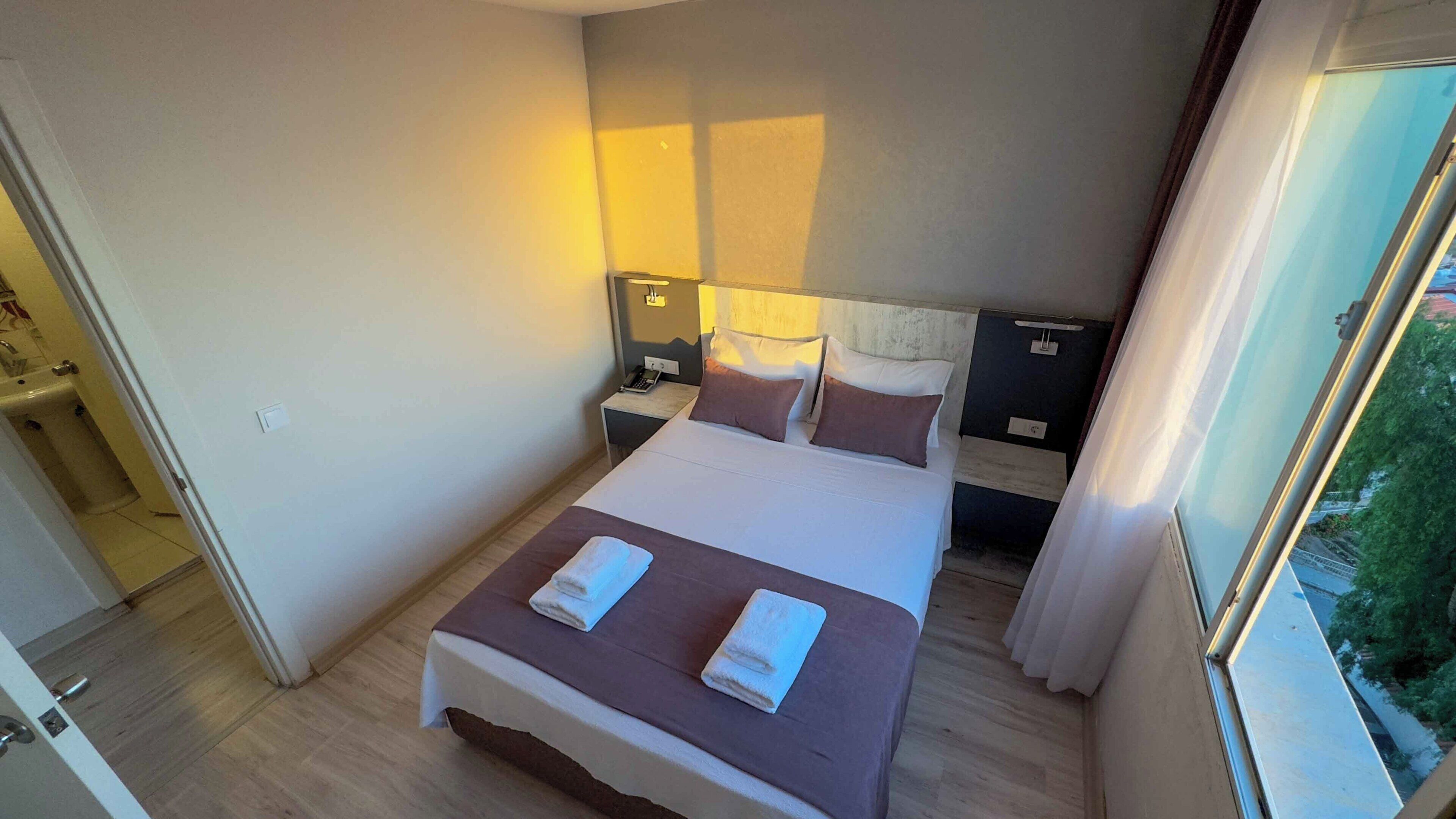 Une chambre d’hôtel avec un lit, des tables de chevet, un téléphone et une fenêtre donnant sur un paysage agréable.