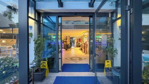 A hotel entrance with glass doors, a reception area, and a blue carpet leading inside. - La Bella Suite Hotel (Kusadasi)