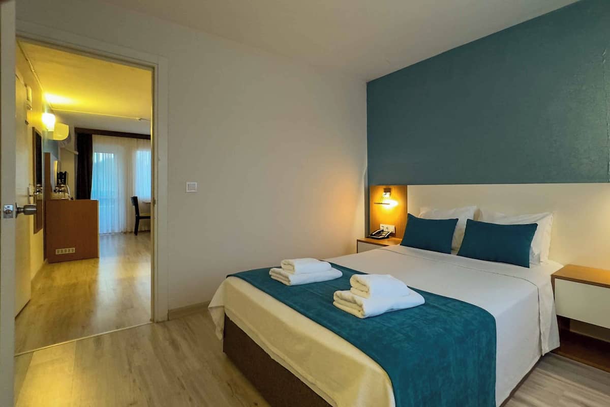 A hotel room with a bed, two bedside tables, a nightstand, a desk, and a chair.