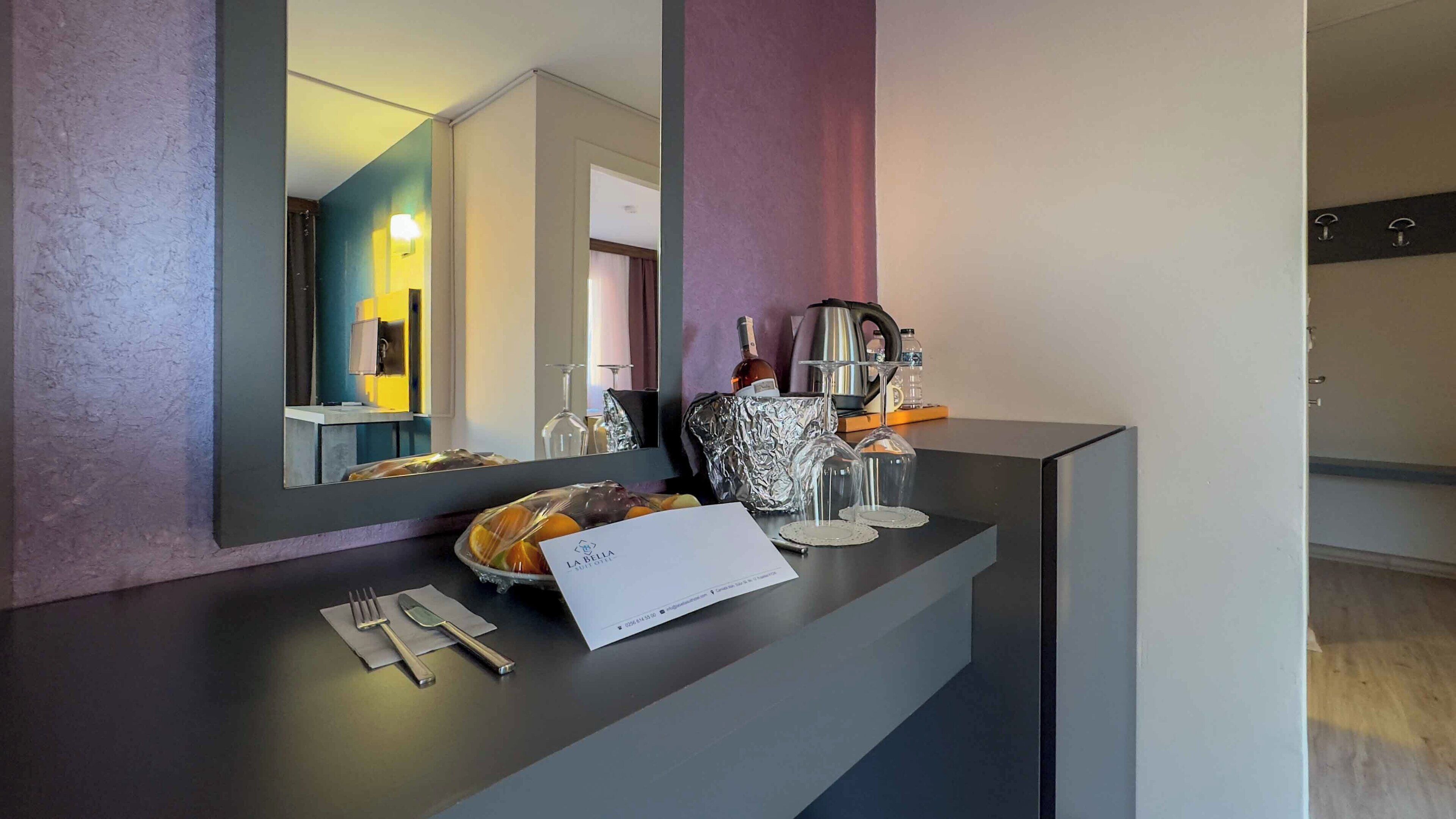 A hotel reception area with a modern counter, a large mirror, and a sign indicating the name of the hotel.