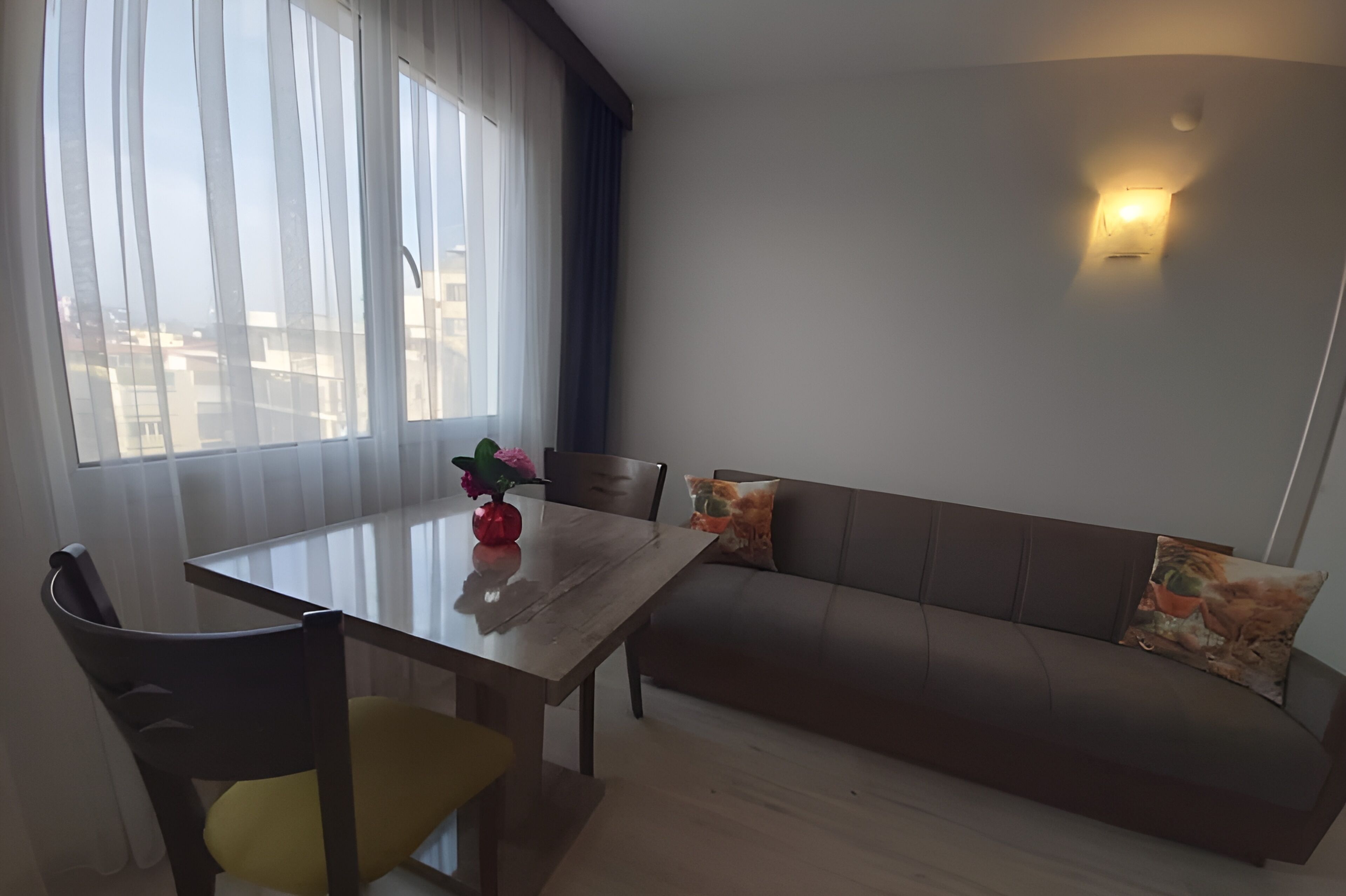Una sala de estar moderna con una mesa de comedor de madera, un sofá y una lámpara fijada a la pared.