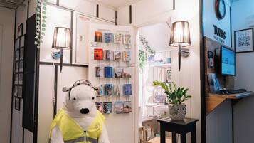 Una habitación con un oso polar como mascota, una estantería, una lámpara y una pequeña mesa con una planta.