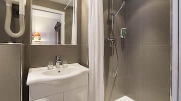 Een badkamer met een wastafel, spiegel, douche en een haardroger.