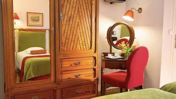 Une chambre à coucher avec une armoire en bois, une table de chevet avec un miroir, une chaise rouge et un lit avec une literie verte.