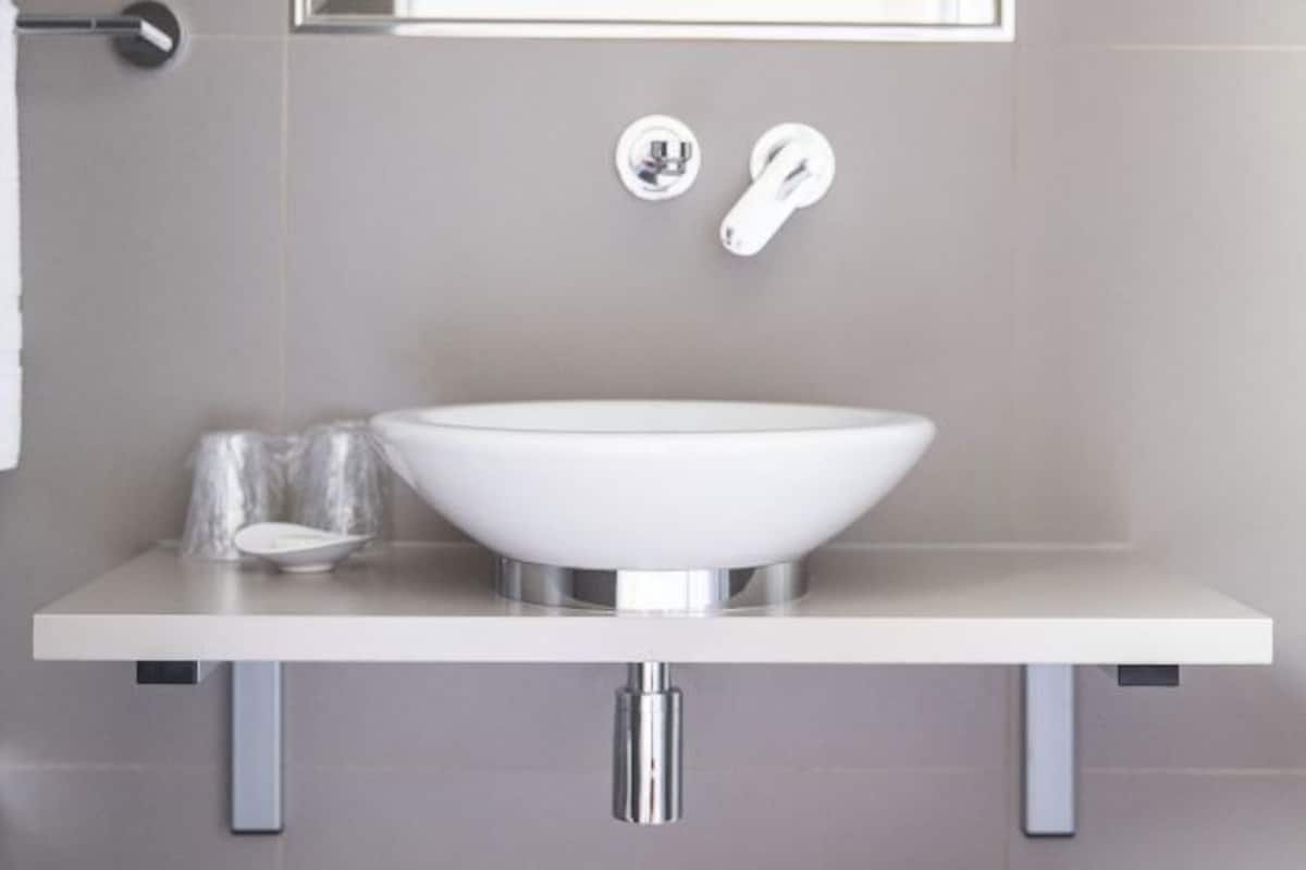 A bathroom with a white sink, chrome faucet, and a mirror above it.