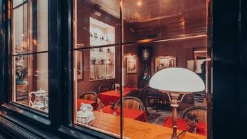 A cozy restaurant with wicker chairs, a wooden table, and a large window.
