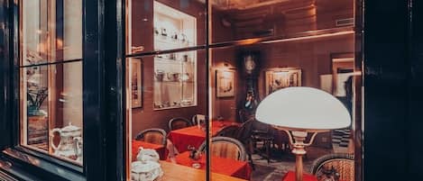 A cozy restaurant with wicker chairs, a wooden table, and a large window.