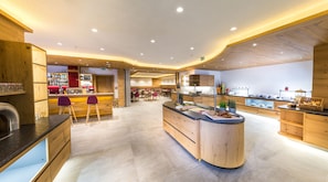 A modern restaurant with a central bar area, wooden accents, and a casual dining space. - Hotel Grüner Baum (Zell am See)