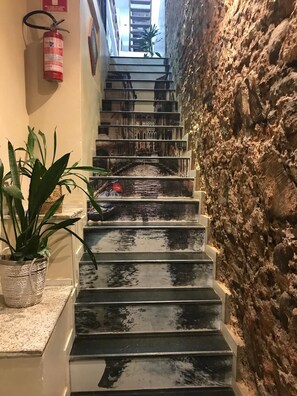 A staircase with a stone wall on one side and a fire extinguisher on the wall. - Pousada Bahia Morena (Salvador)