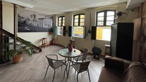 A dining area with a round table and four chairs, a sofa, a potted plant, and a large wall-mounted picture.