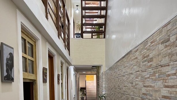 A narrow hallway with a bench, tiled flooring, and a wall with a stone-like pattern.