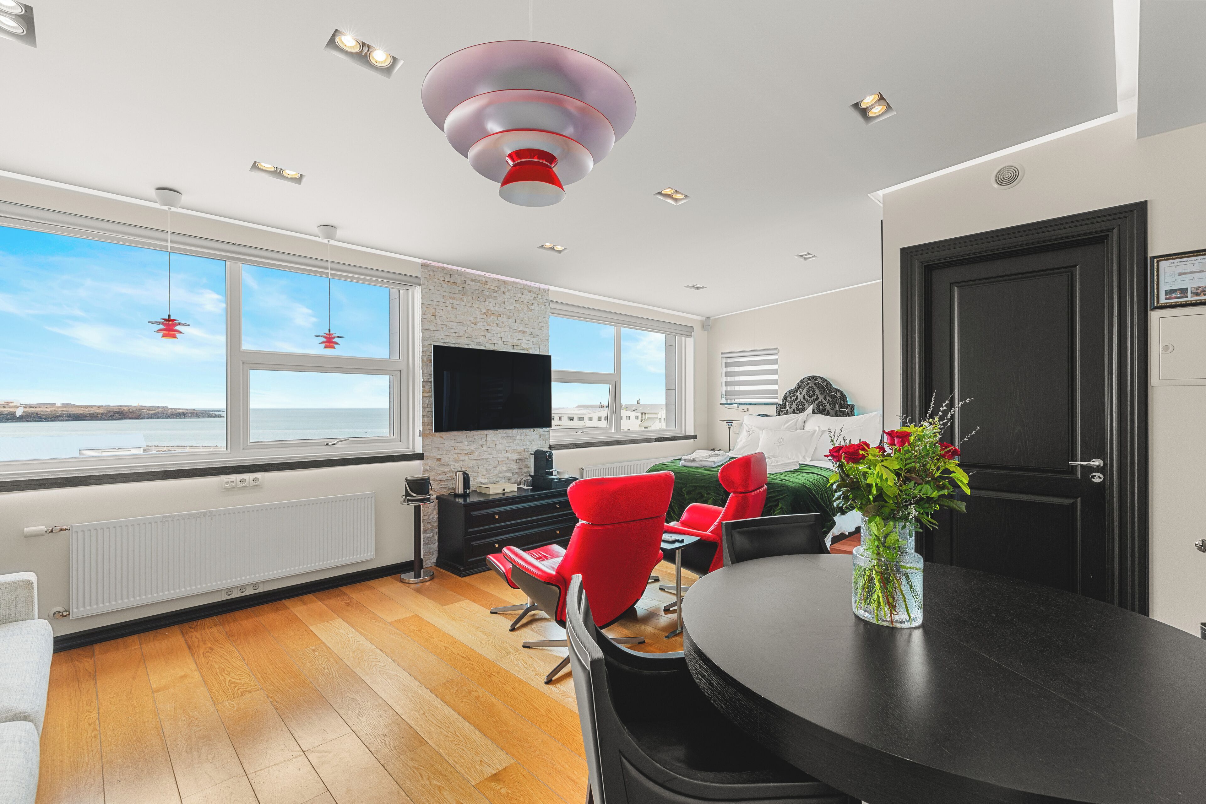 Uma sala de estar moderna com uma janela grande, uma lareira e um espaço de jantar com mesa e cadeiras.