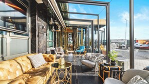 A modern lounge area with leather sofas, a glass wall, and a view of the street. - Diamond Suites by Reykjavik Keflavik Airport (Reykjanesbær)