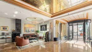 A spacious lobby with a marble floor, leather seating, a fireplace, and a large painting. - Diamond Suites by Reykjavik Keflavik Airport (Reykjanesbær)
