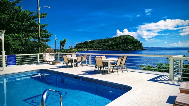 A pool area with lounge chairs and a view of the ocean. - Beachcombers Hotel (Villa)