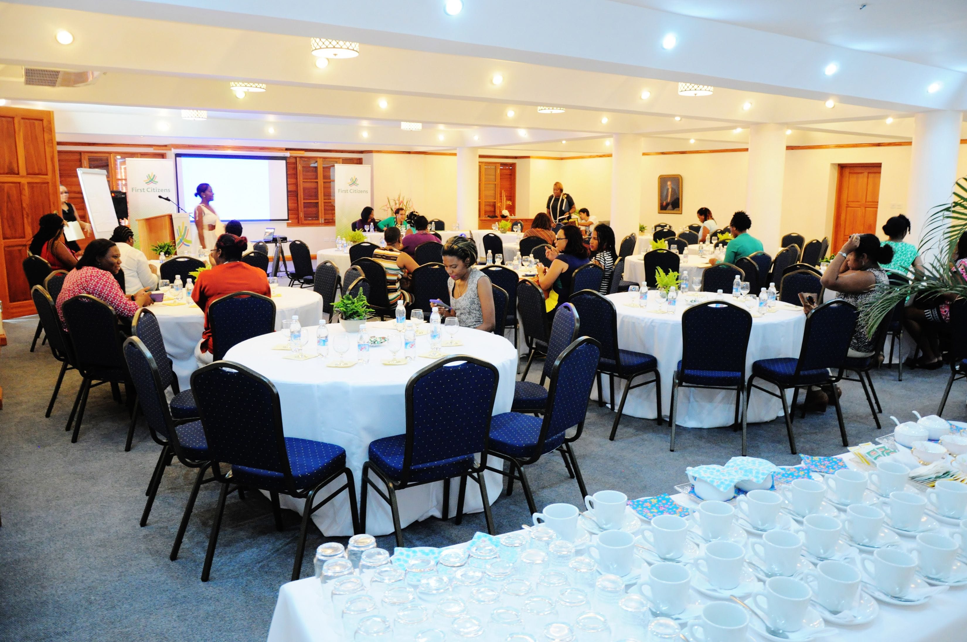 A conference room with round tables, chairs, and a presentation screen.