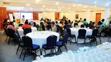 A conference room with round tables, chairs, and a presentation screen.