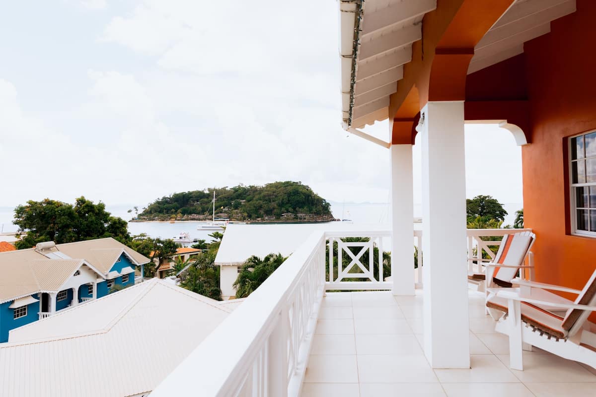A balcony with white railings, a view of a small island, and a body of water.