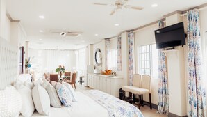 A spacious bedroom with a large bed, a desk, and a television. - Beachcombers Hotel (Villa)