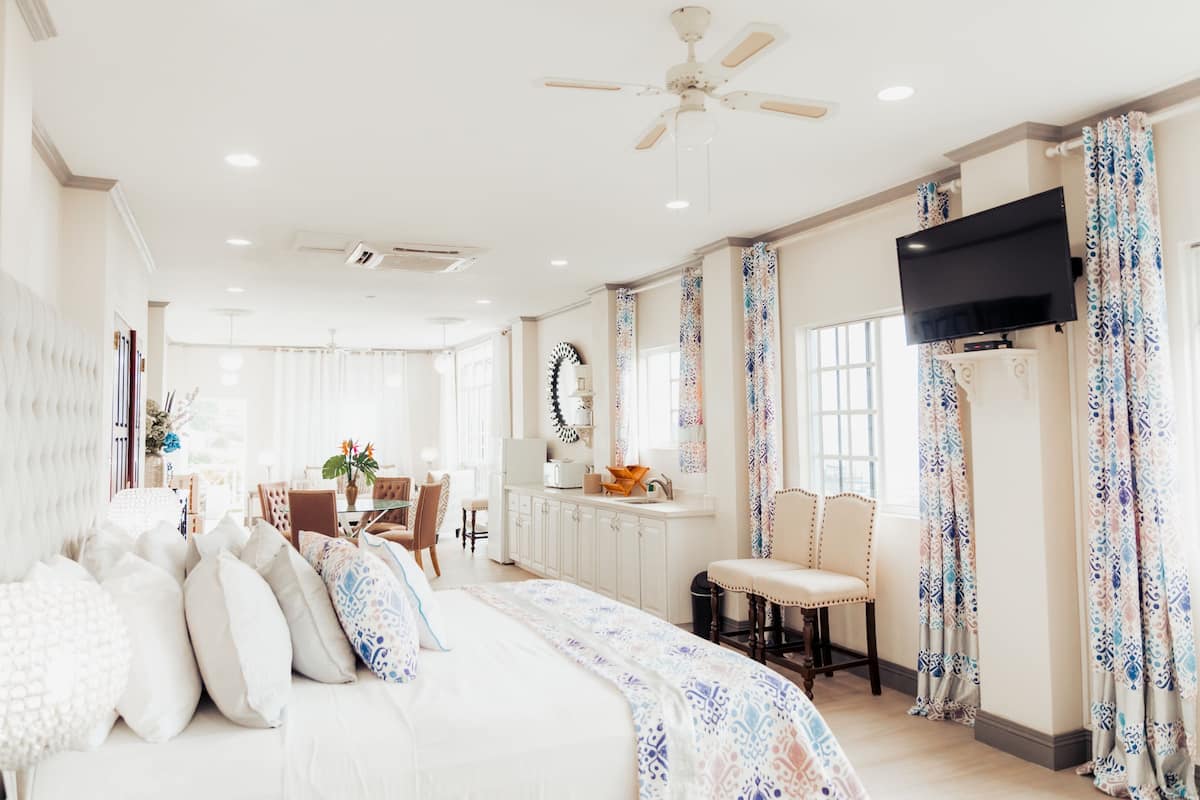 A spacious bedroom with a large bed, a desk, and a television.