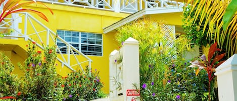 Un edificio amarillo con una escalera blanca que lleva a un balcón.