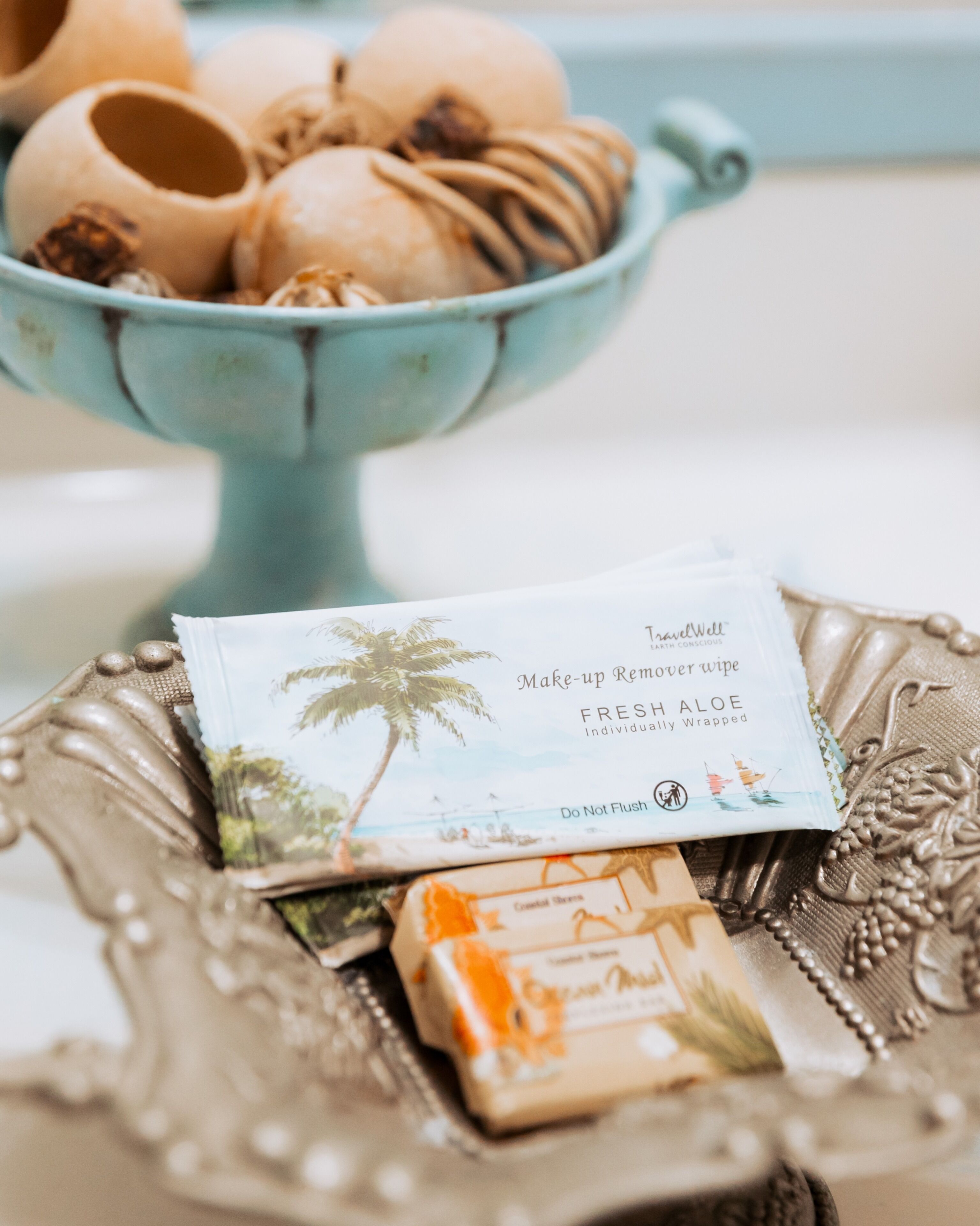 A tray with a makeup remover wipe, a bar of soap, and a bowl of coconut shells.