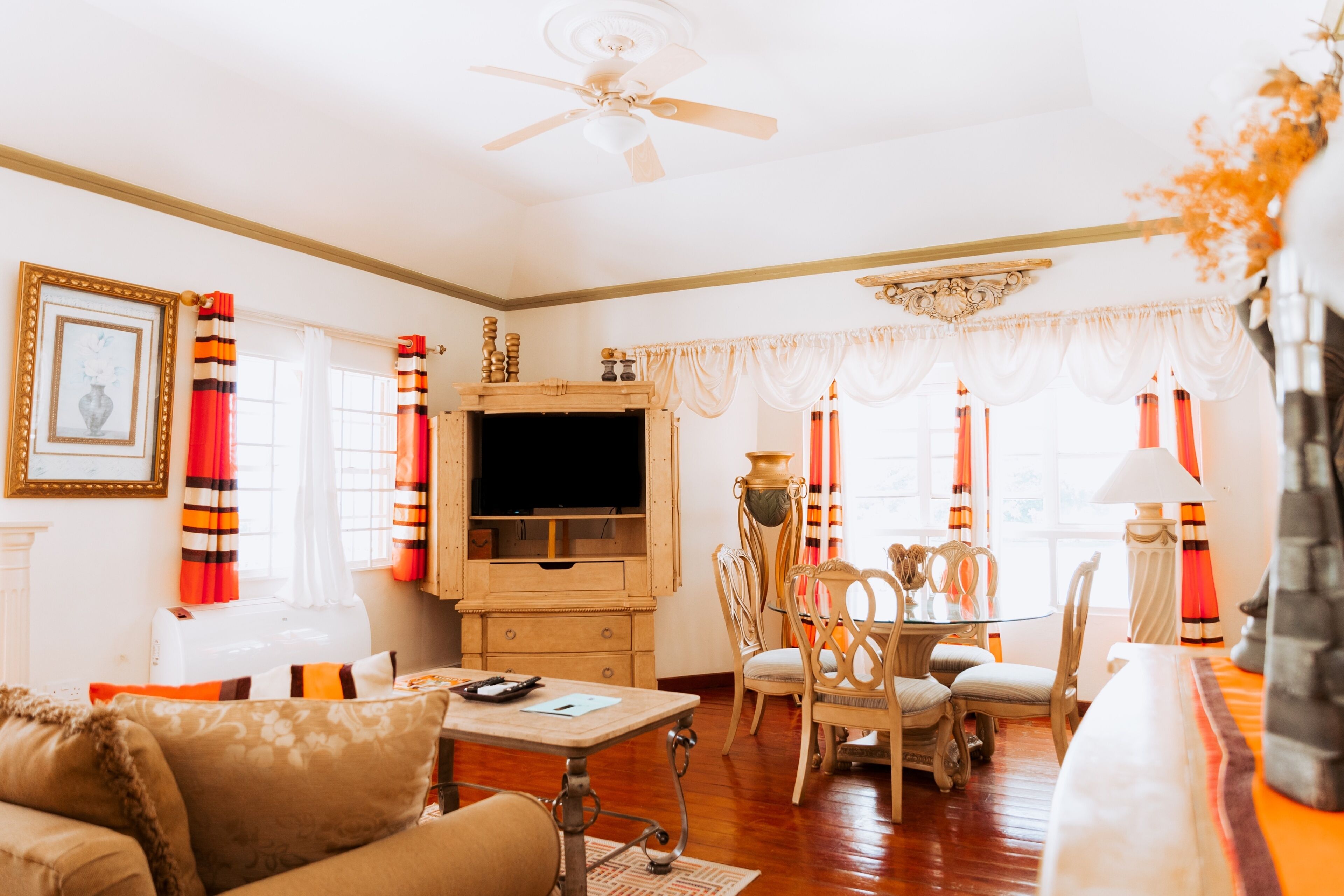 A living room with a fireplace, a television, a dining table with chairs, and a ceiling fan.
