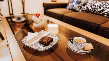 A cozy living area with a glass coffee table, a plate with a piece of cake, a cup of coffee, and a candle.