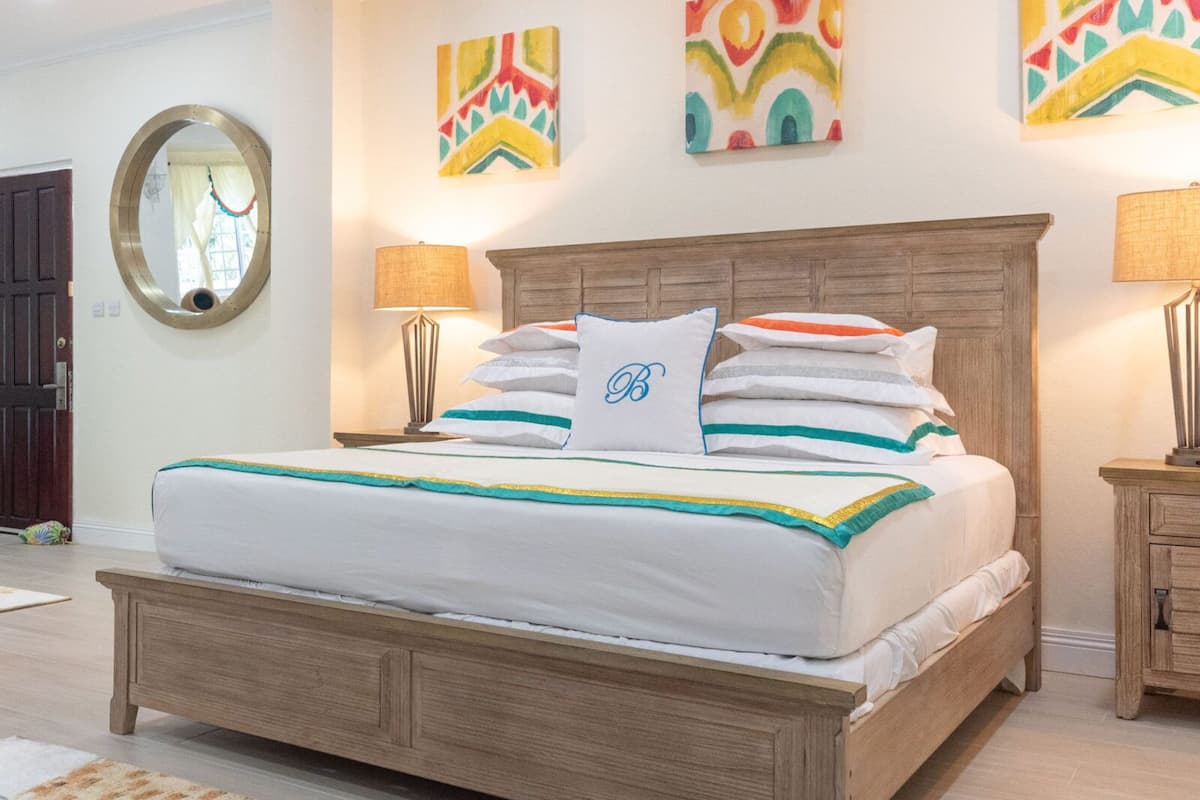 A bedroom with a wooden bed, two bedside tables, a mirror, and colorful wall art.