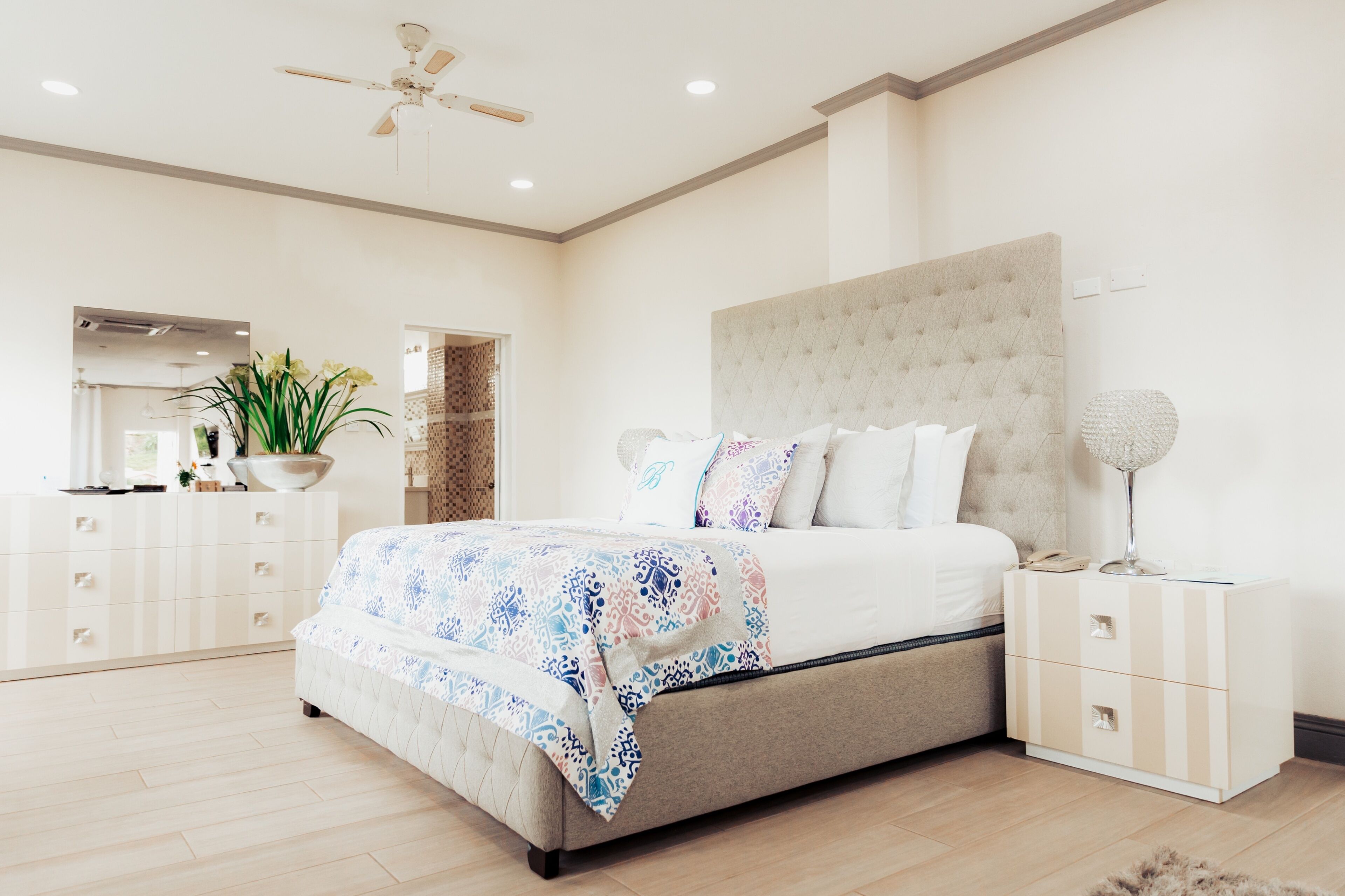 Un dormitorio con una cama grande, una mesita de noche, un tocador y un abanico de techo.