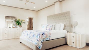 Un dormitorio con una cama grande, una mesita de noche, un tocador y un abanico de techo.