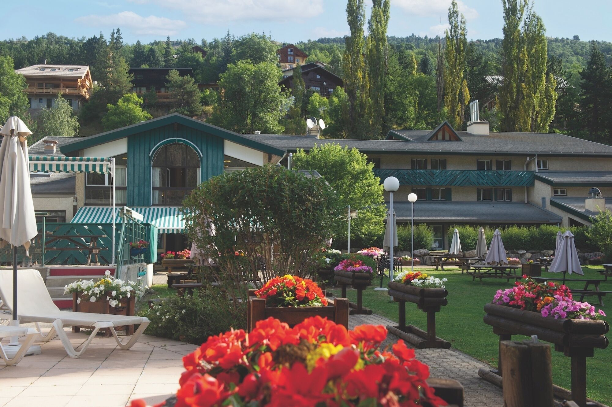 Een resort met terras, bloembedden en uitzicht op omliggende gebouwen.