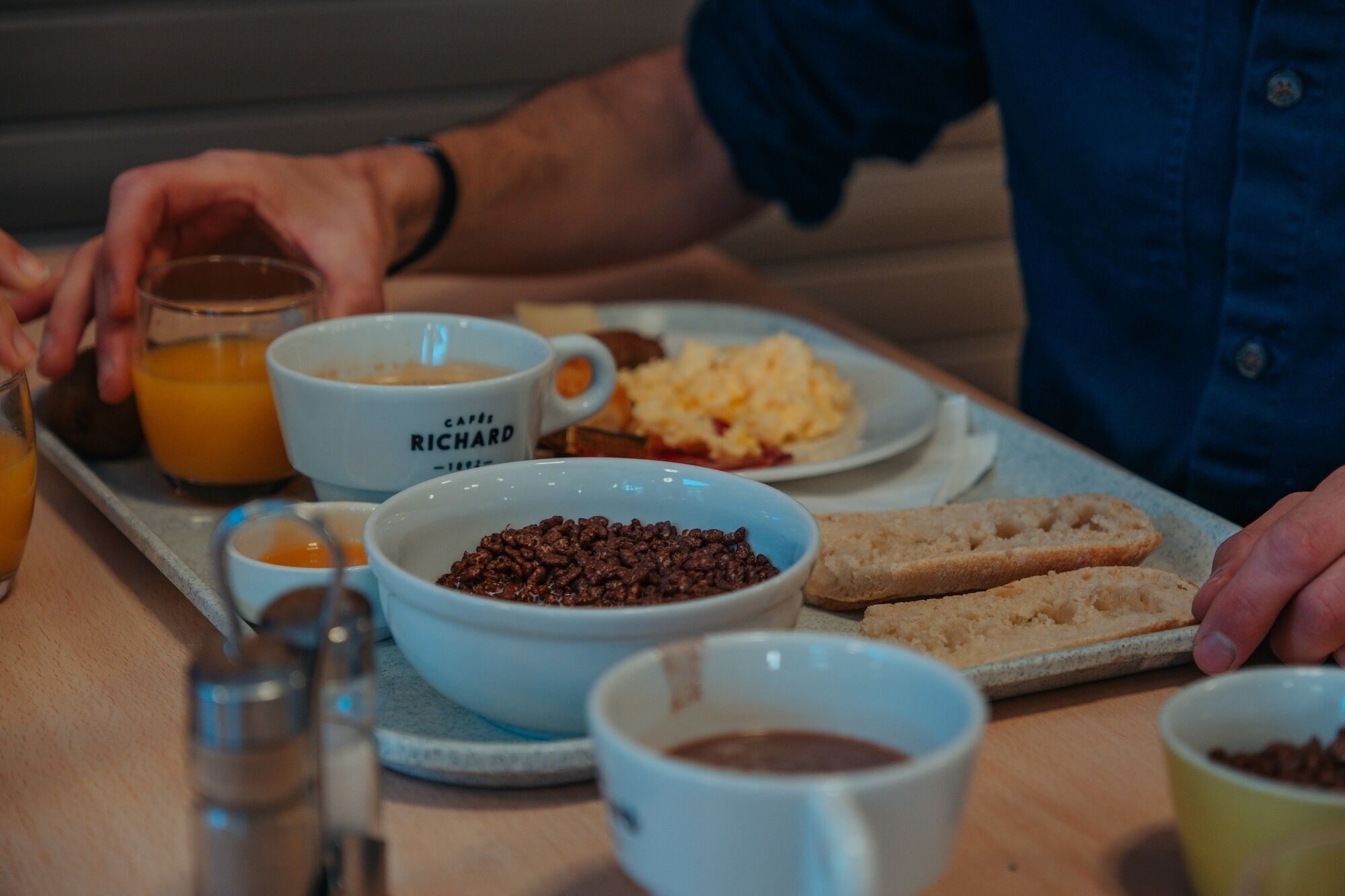 Bandeja de desayuno con café, huevos revueltos, tostadas y un tazón de chocolate.