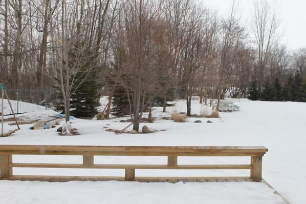 A wooden bench in a snowy park with bare trees and a fence in the background. - Auberge Motel Le Pigeonnier (Farnham)