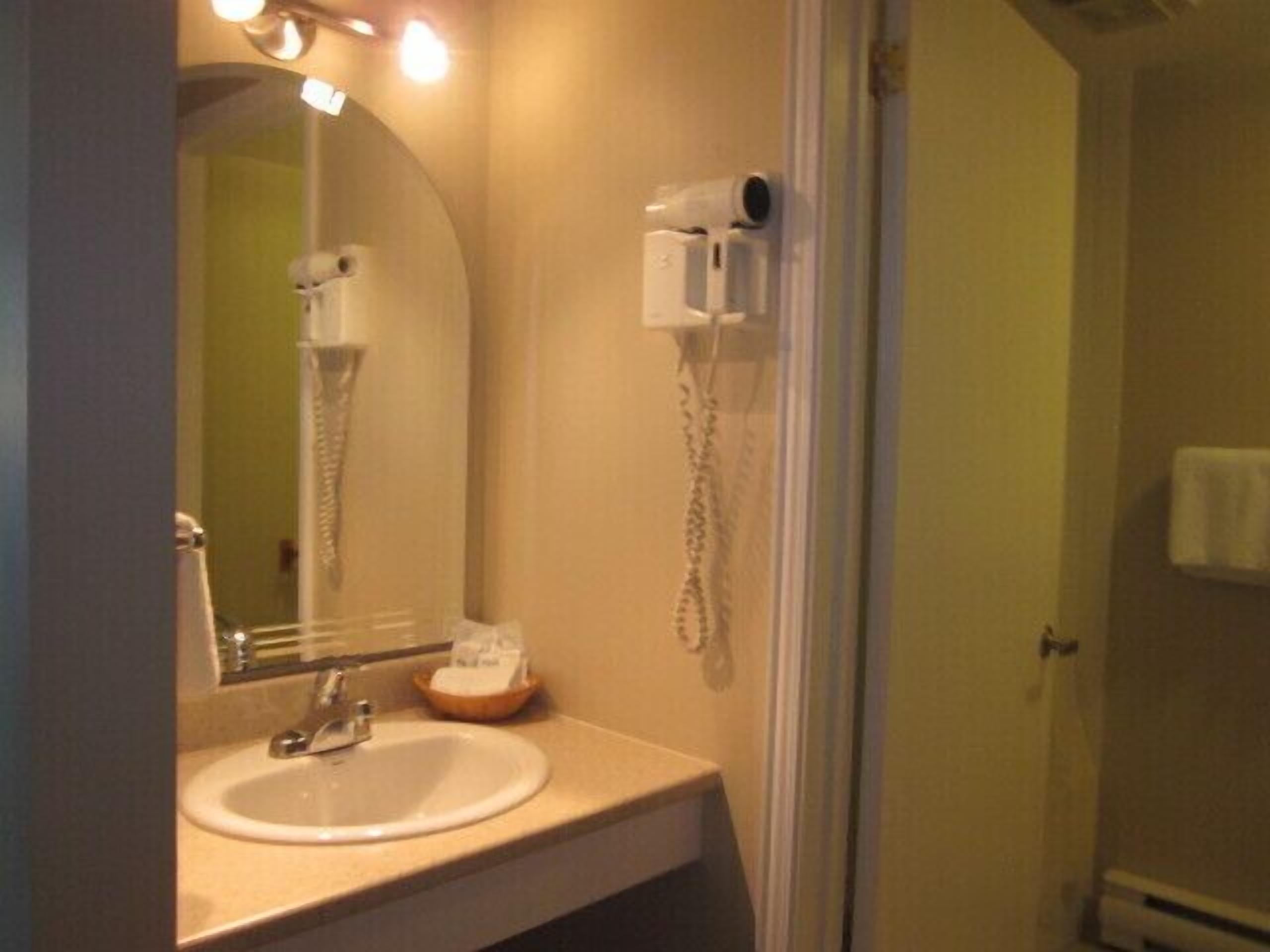 A bathroom with a sink, mirror, hairdryer, and towel rack.