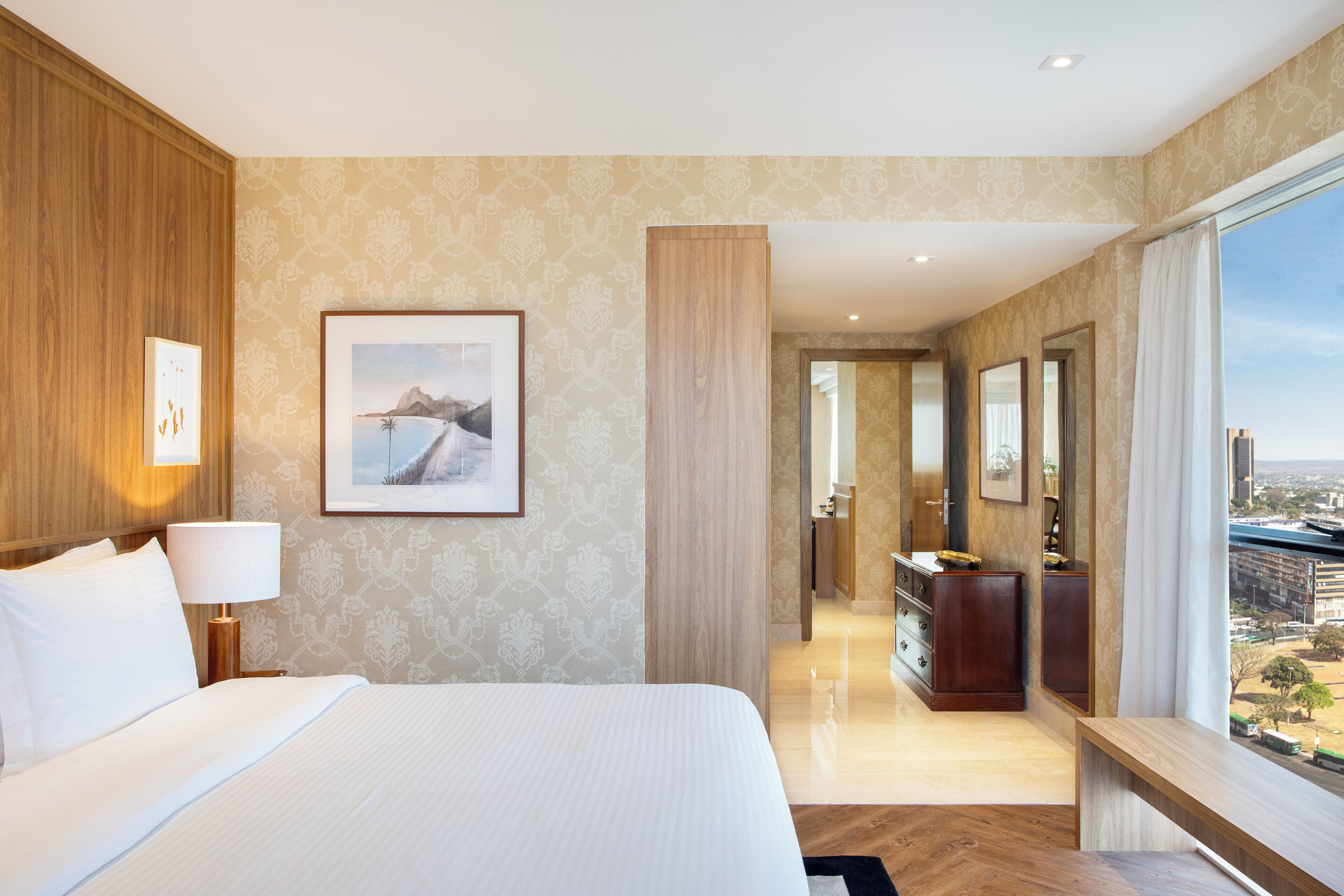 A hotel room with a large bed, a desk, and a view of the city.