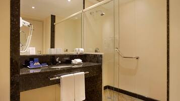 A modern bathroom with a glass-enclosed shower, a marble sink, and a large mirror.