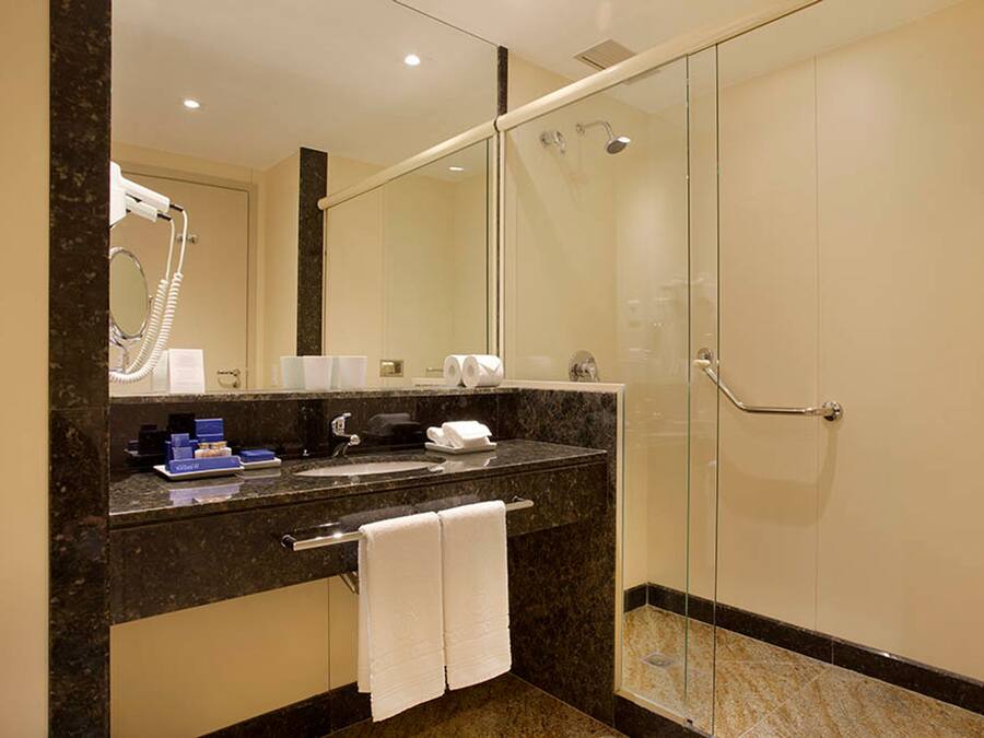 A modern bathroom with a glass-enclosed shower, a marble sink, and a large mirror.