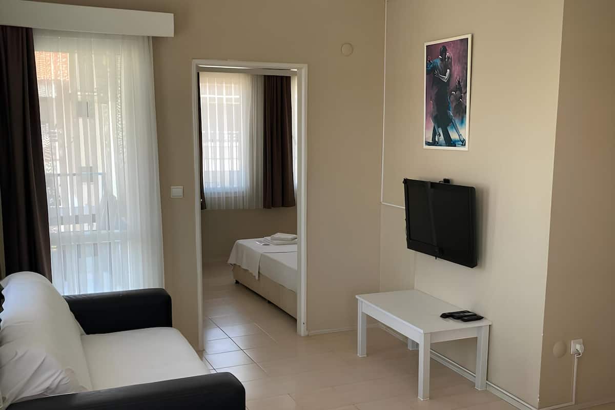 A hotel room with a bed, a sofa, a TV, and a small table.