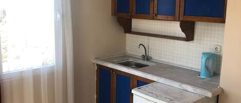 A compact kitchen with a sink, a small refrigerator, and blue cabinets.