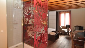 A hotel room with a shower, a bed, a sitting area with a table and chairs, and a window with curtains. - Hostal de Cabrit (Sant Mateu)