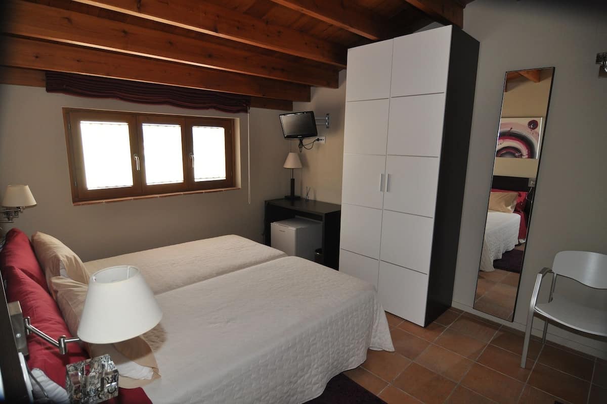 A bedroom with two beds, a wardrobe, a desk, and a mirror.
