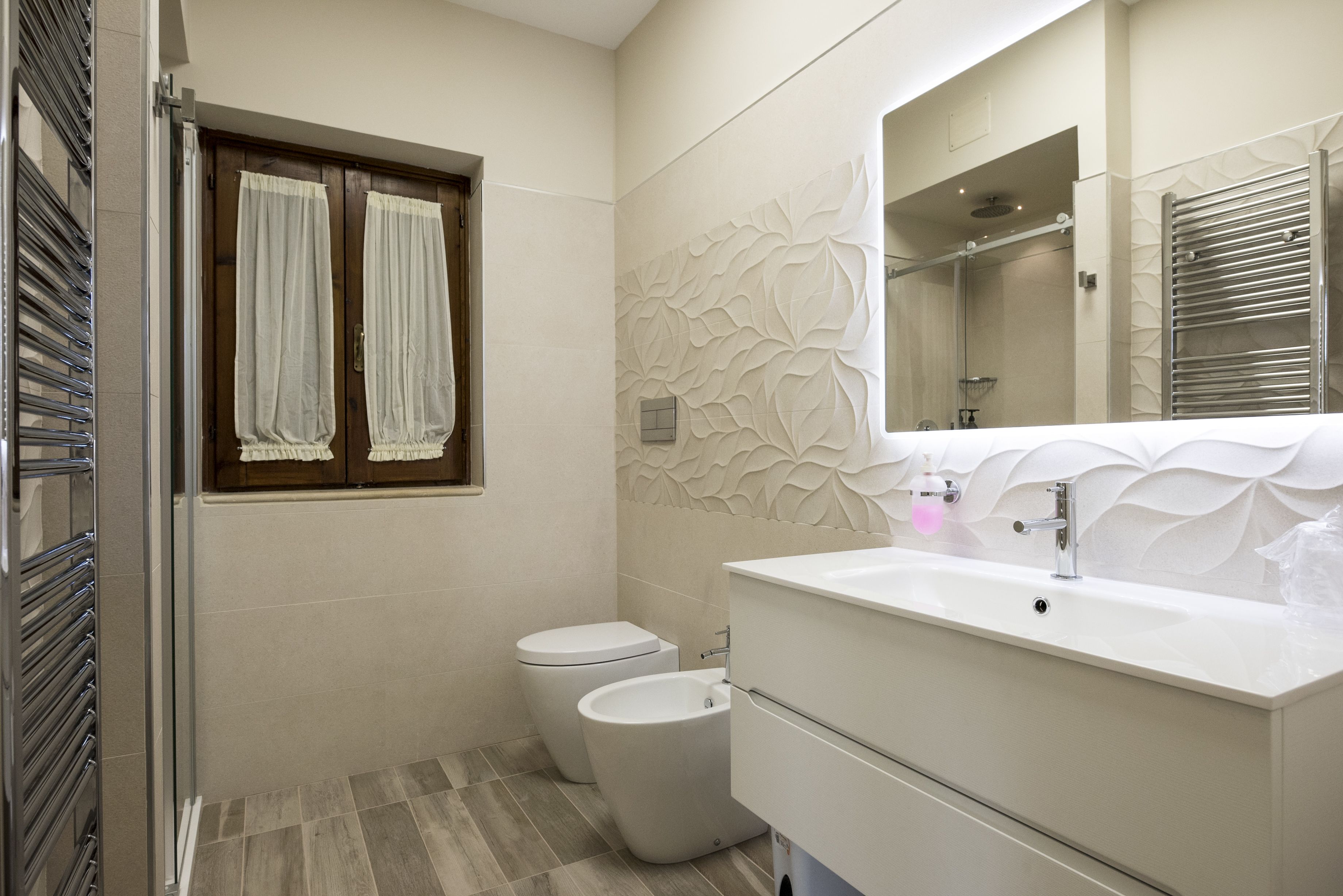 Un bany modern amb vàter, bidet i un lavabo amb mirall.