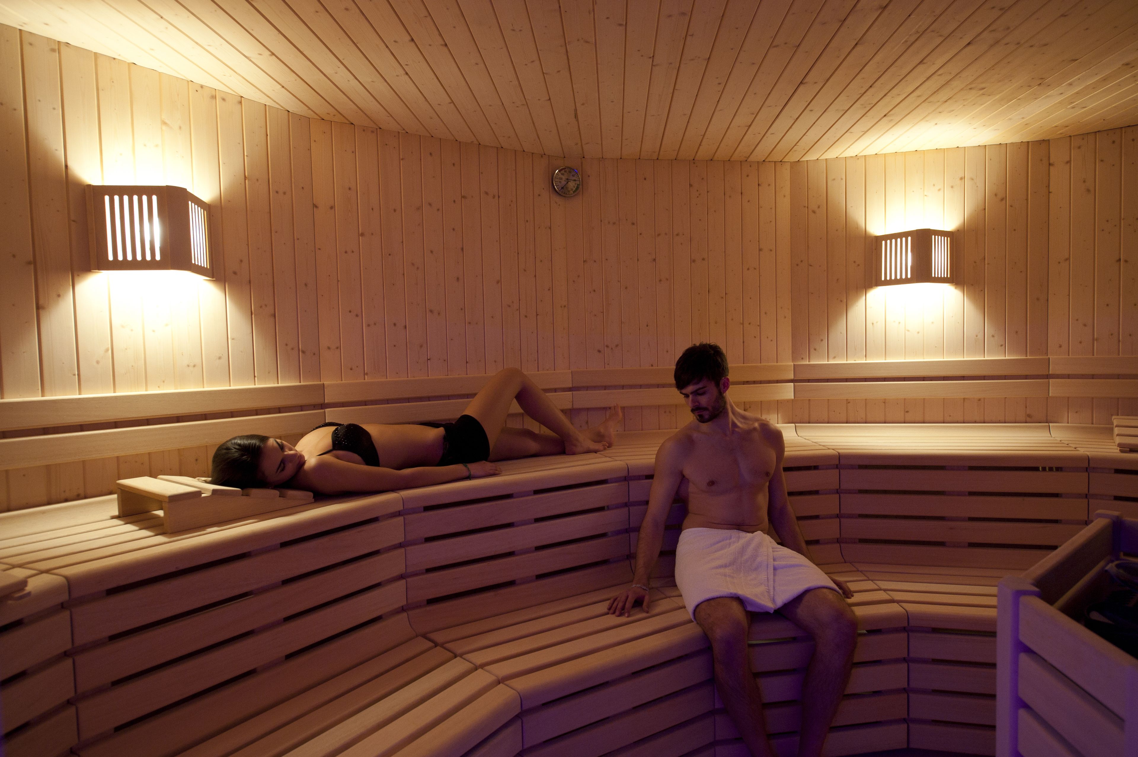 A sauna with wooden benches and wall-mounted lights.