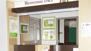 A reception desk with a sign reading "Bienvenue chez B&B" and a map on the wall.