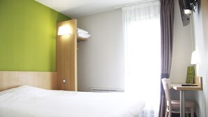 A hotel room with a bed, a desk, and a chair.