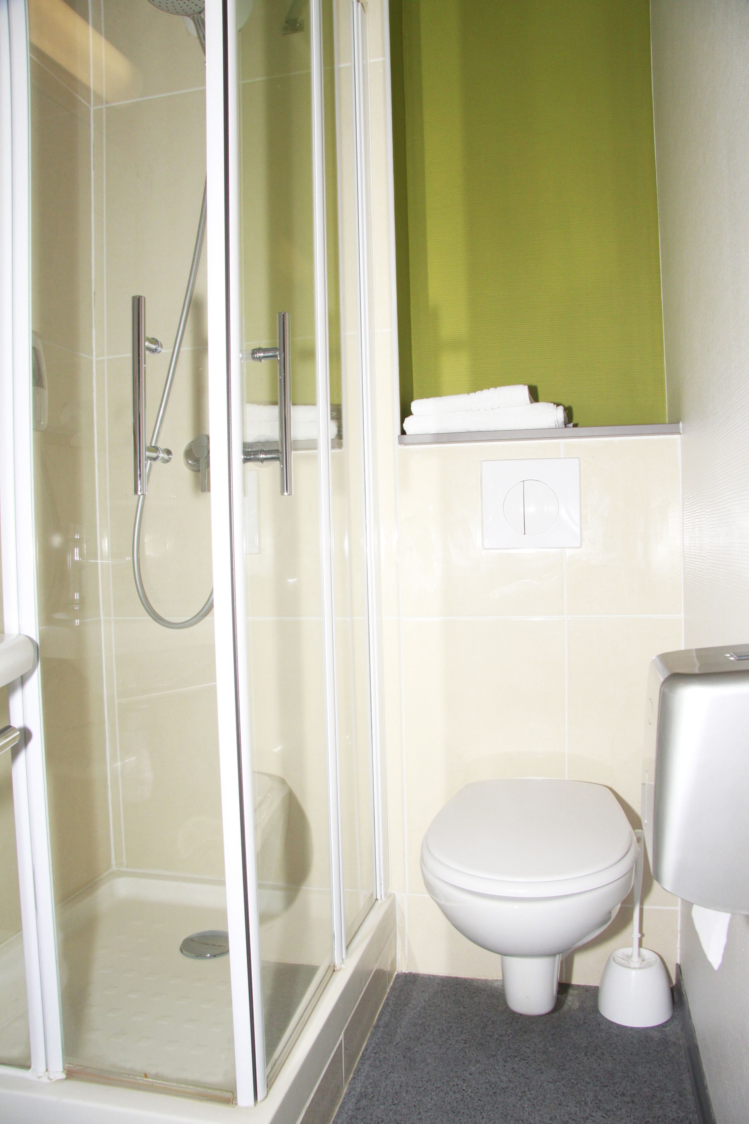 Ein Badezimmer mit Duschkabine, Toilette und Handtuchhalter.