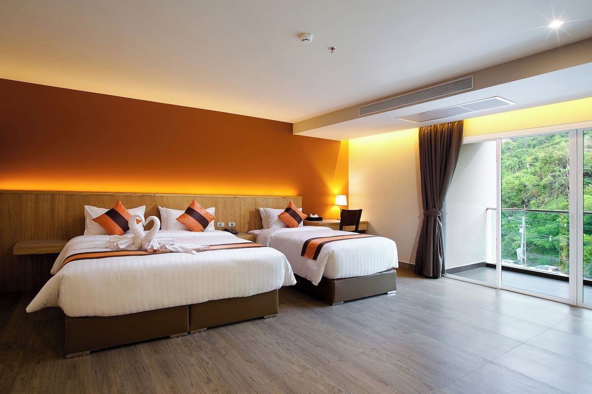 Hotellihuone, jossa on kaksi sänkyä, suuri ikkuna ja näkymä vehreään maisemaan.